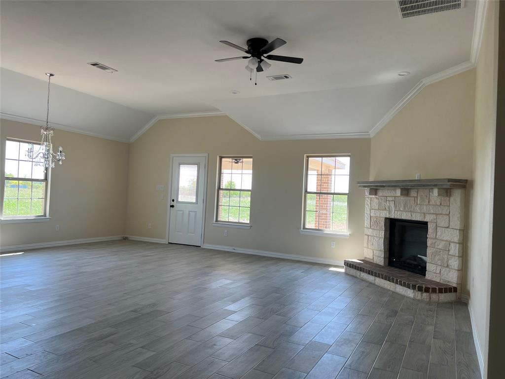 8008 County Road 1058 Rice, TX 75155 - Photo 4 of 25 Spacious living area featuring vaulted ceilings, crown molding, wood-finish tile flooring, and a stone fireplace with a brick hearth
