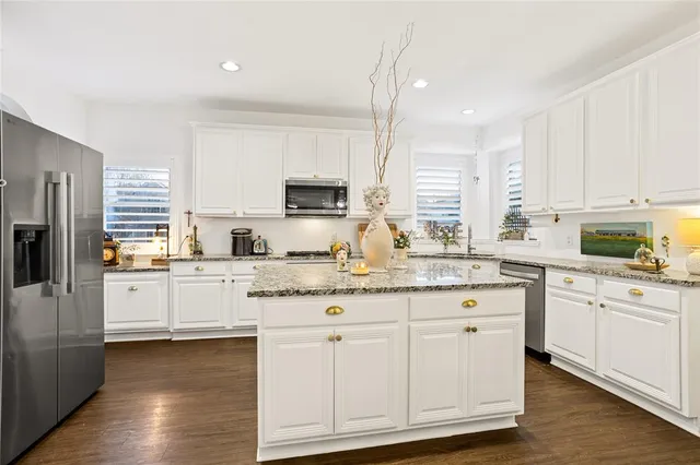 a kitchen with granite countertop white cabinets and white appliances