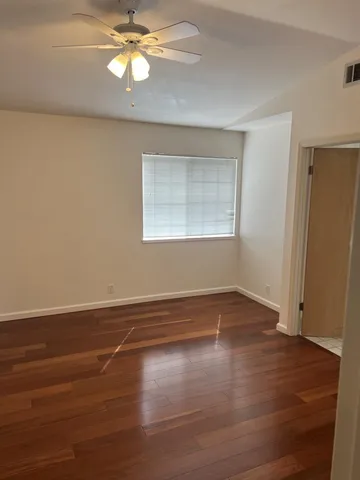 an empty room with wooden floor closet and windows