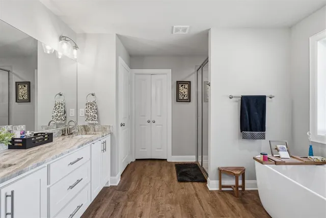 a spacious bathroom with a double vanity sink a mirror and shower