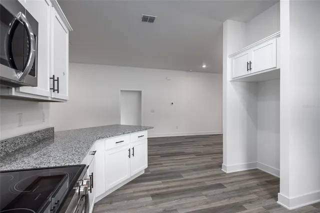 a kitchen with granite countertop a white stove top oven and wooden floor