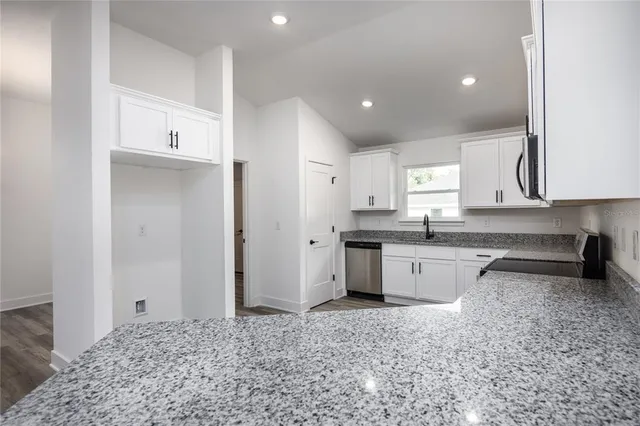 a large white kitchen with granite countertop a sink and cabinets