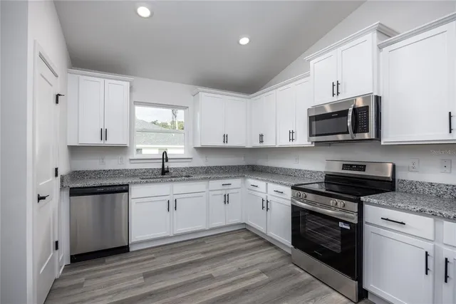 a kitchen with stainless steel appliances granite countertop a stove a sink and a microwave