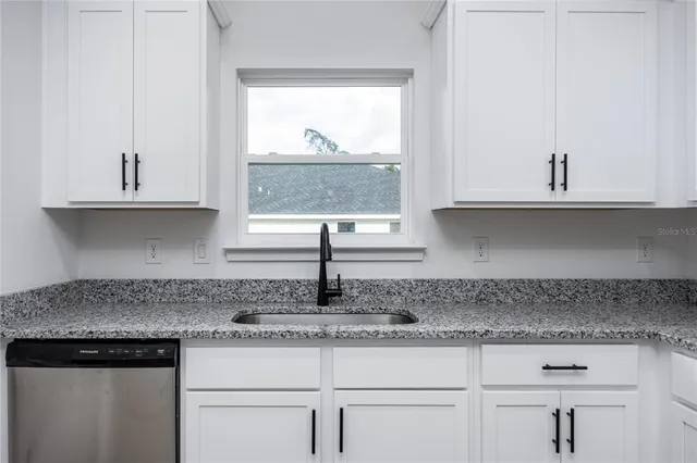 a kitchen with granite countertop white cabinets and a window