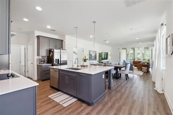 a kitchen with stainless steel appliances a dining table chairs stove refrigerator and cabinets