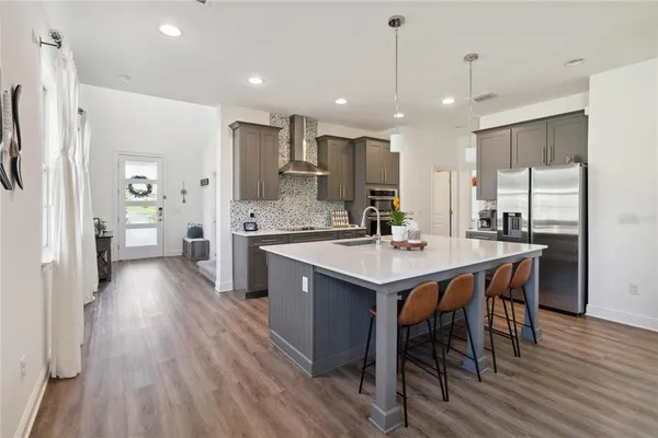 a kitchen with stainless steel appliances granite countertop a sink a stove a refrigerator with a dining table and chairs