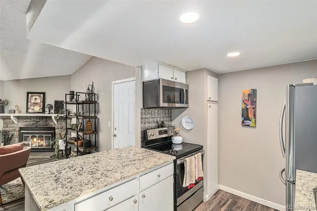 a kitchen with stainless steel appliances granite countertop a refrigerator and a stove top oven