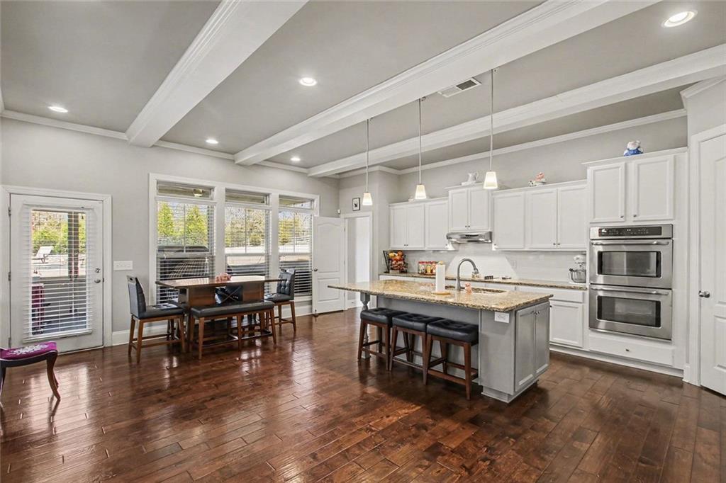 971 Traditions Way Jefferson, GA 30549 - Photo 11 of 53 a kitchen with kitchen island a dining table chairs and wooden floor