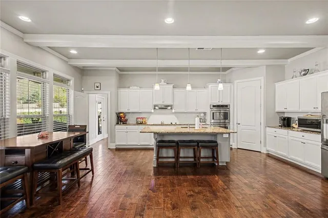 a large white kitchen with lots of counter space and breakfast area