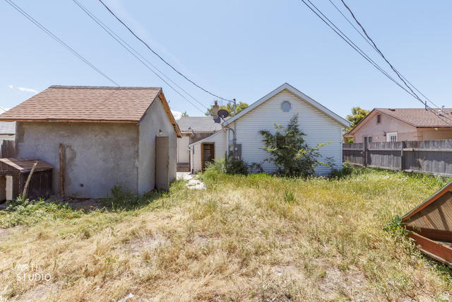 330 West 600th Street South Provo, UT 84601 - Photo 25 of 26 Expansive backyard space featuring a detached auxiliary structure with a shingled roof, a white-sided rear exterior, and a wooden fence along the property line