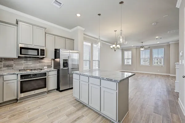a kitchen with stainless steel appliances granite countertop hardwood floor sink stove dining table and chairs