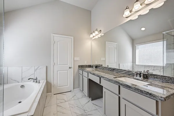 a spacious bathroom with a granite countertop sink a large mirror and a bathtub