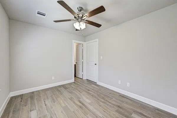 an empty room with wooden floor and ceiling fan
