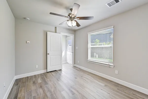 a view of an empty room with wooden floor and a window