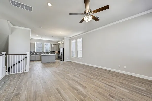 a view of an empty room with wooden floor and a ceiling fan