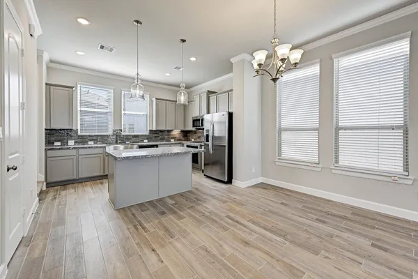 a large kitchen with kitchen island a stove a sink dishwasher and a refrigerator with wooden floor