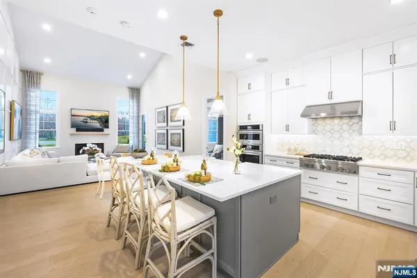 a kitchen with stainless steel appliances kitchen island granite countertop a stove a sink a dining table and chairs with wooden floor