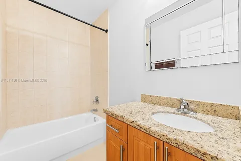 a bathroom with a granite countertop sink and a bathtub