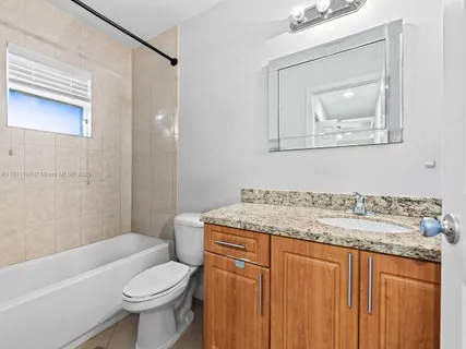 a bathroom with a granite countertop sink mirror vanity and toilet