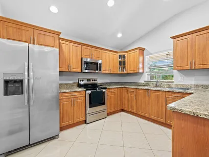 a kitchen with stainless steel appliances granite countertop a refrigerator sink and stove
