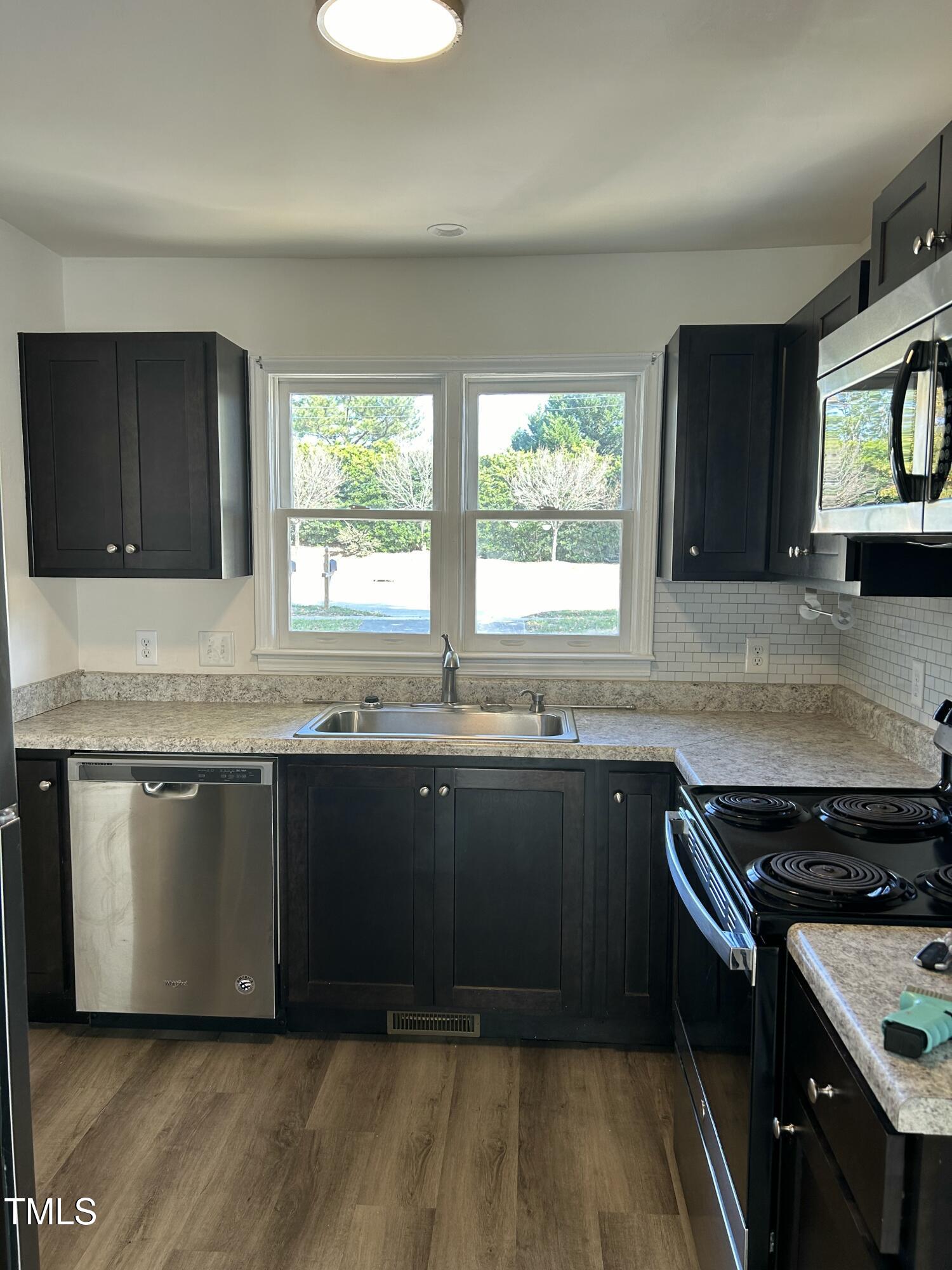 8107 Perry Creek Raleigh, NC 27616 - Photo 5 of 10 a kitchen with granite countertop a stove a sink and a microwave