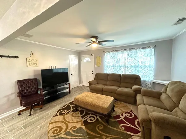 a living room with furniture a flat screen tv and a window