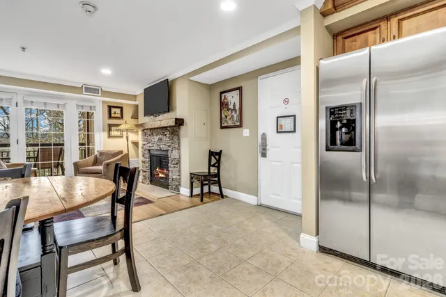 a kitchen with stainless steel appliances granite countertop a refrigerator oven stove a sink a dining table and chairs with wooden floor