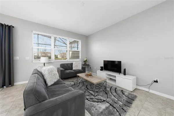 a living room with furniture a flat screen tv and a window