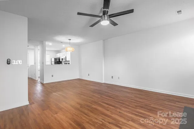 a view of a livingroom with a fireplace a ceiling fan and wooden floor