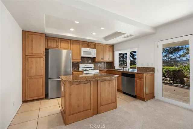 a kitchen with stainless steel appliances granite countertop a refrigerator oven a sink a dining table and chairs