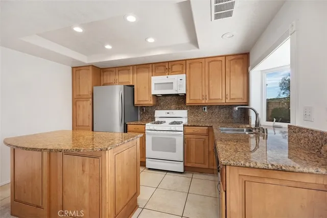 a kitchen with stainless steel appliances granite countertop a stove a sink dishwasher and a refrigerator