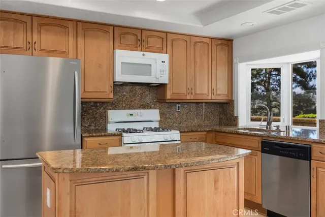 a kitchen with stainless steel appliances granite countertop a sink and a refrigerator