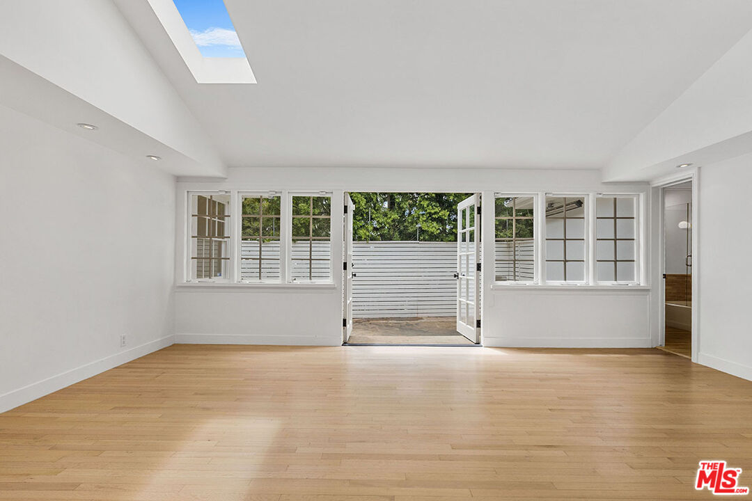 1462 Rising Glen Road Los Angeles, CA 90069 - Photo 16 of 40 an empty room with wooden floor and windows