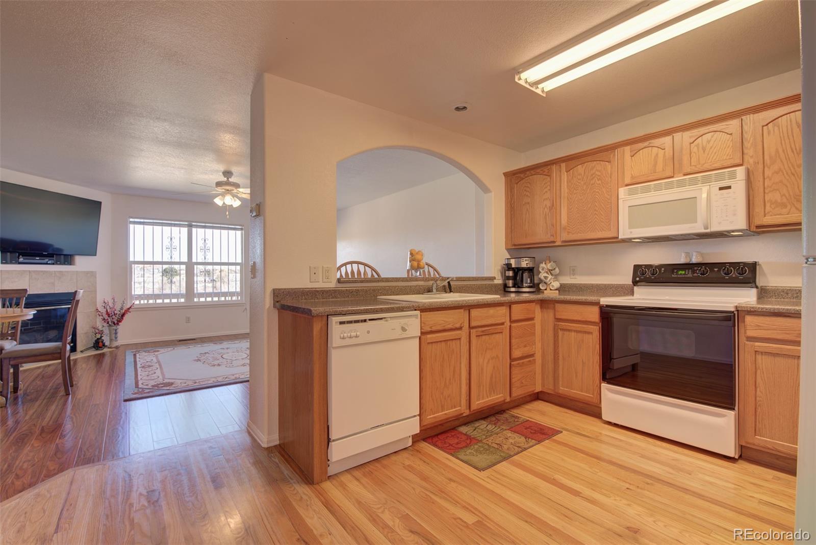 3563 Indigo Ridge Point Colorado Springs, CO 80910 - Photo 5 of 28 a kitchen with granite countertop a stove top oven a sink dishwasher and white cabinets with wooden floor