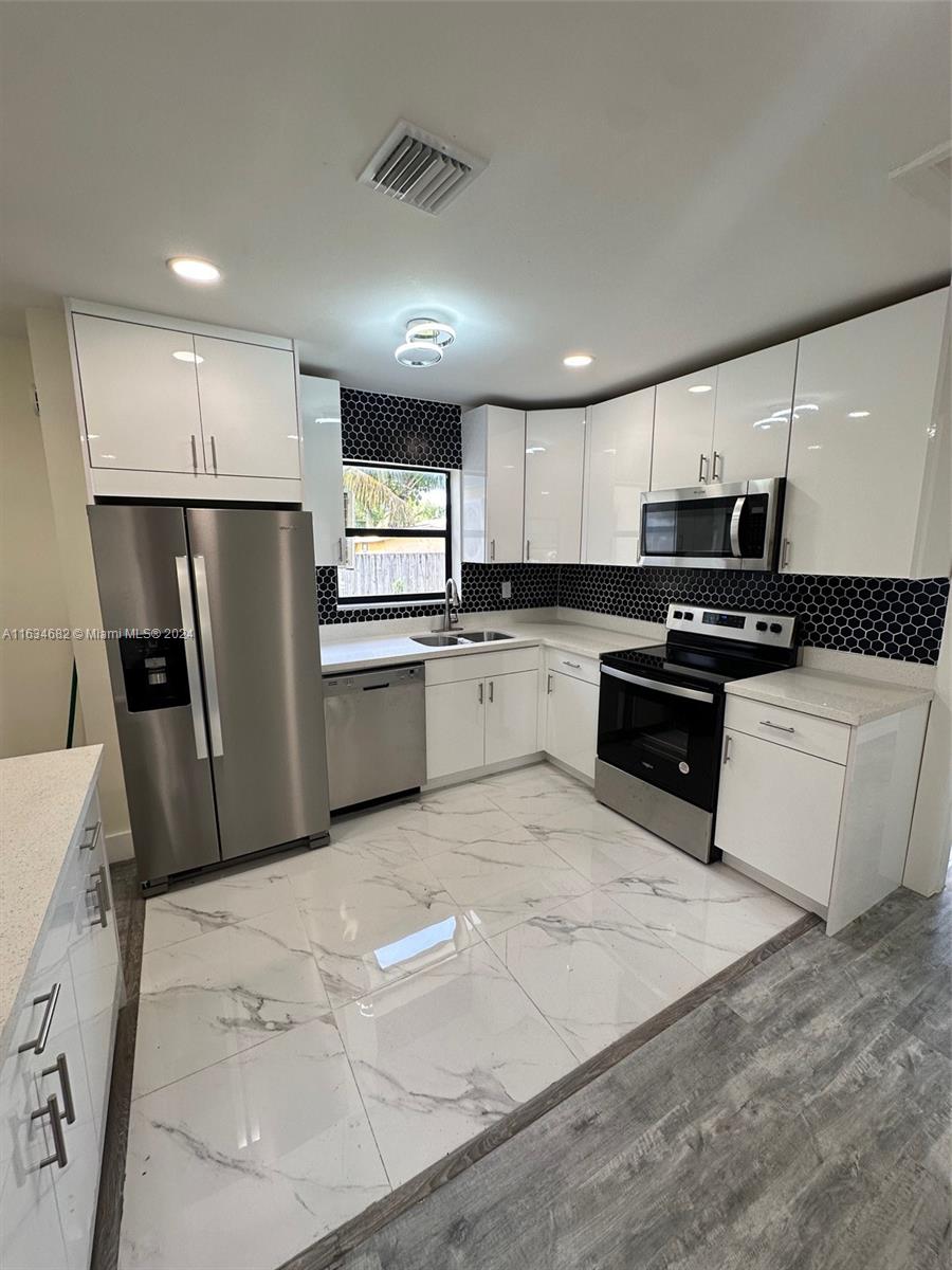 6517 Wiley Street Hollywood, FL 33023 - Photo 5 of 17 a kitchen with granite countertop a refrigerator sink and microwave