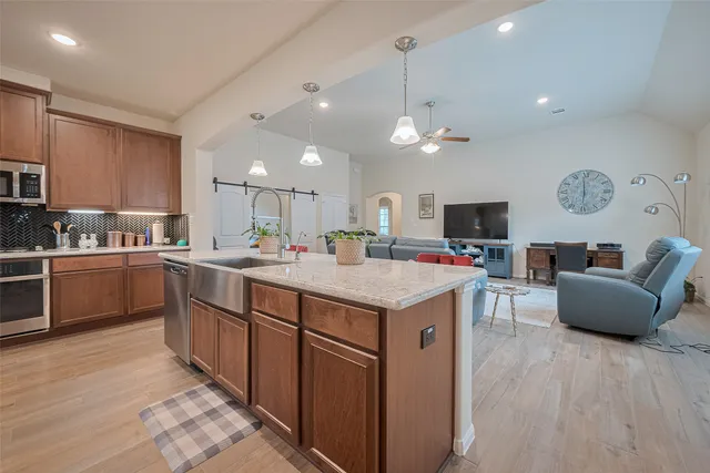 a kitchen with kitchen island granite countertop a sink a counter top space and stainless steel appliances