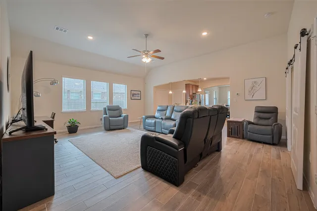 a living room with furniture a large window and wooden floor