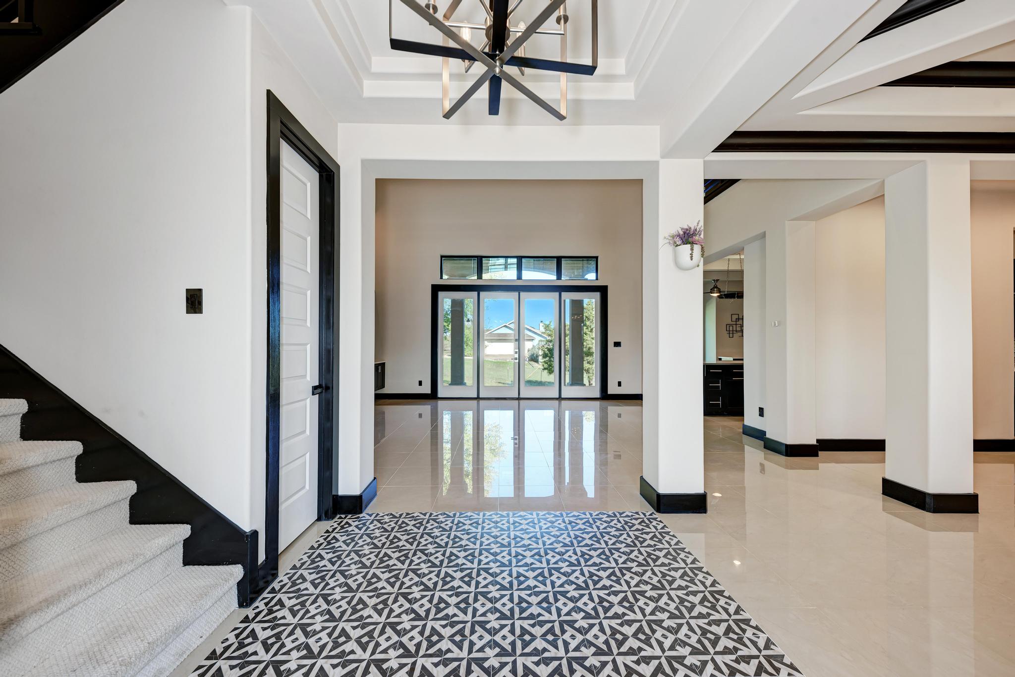 104 Spring Valley Street Hutto, TX 78634 - Photo 9 of 40 Foyer entrance with light tile patterned floors, a chandelier, stairway, crown molding, and a raised ceiling