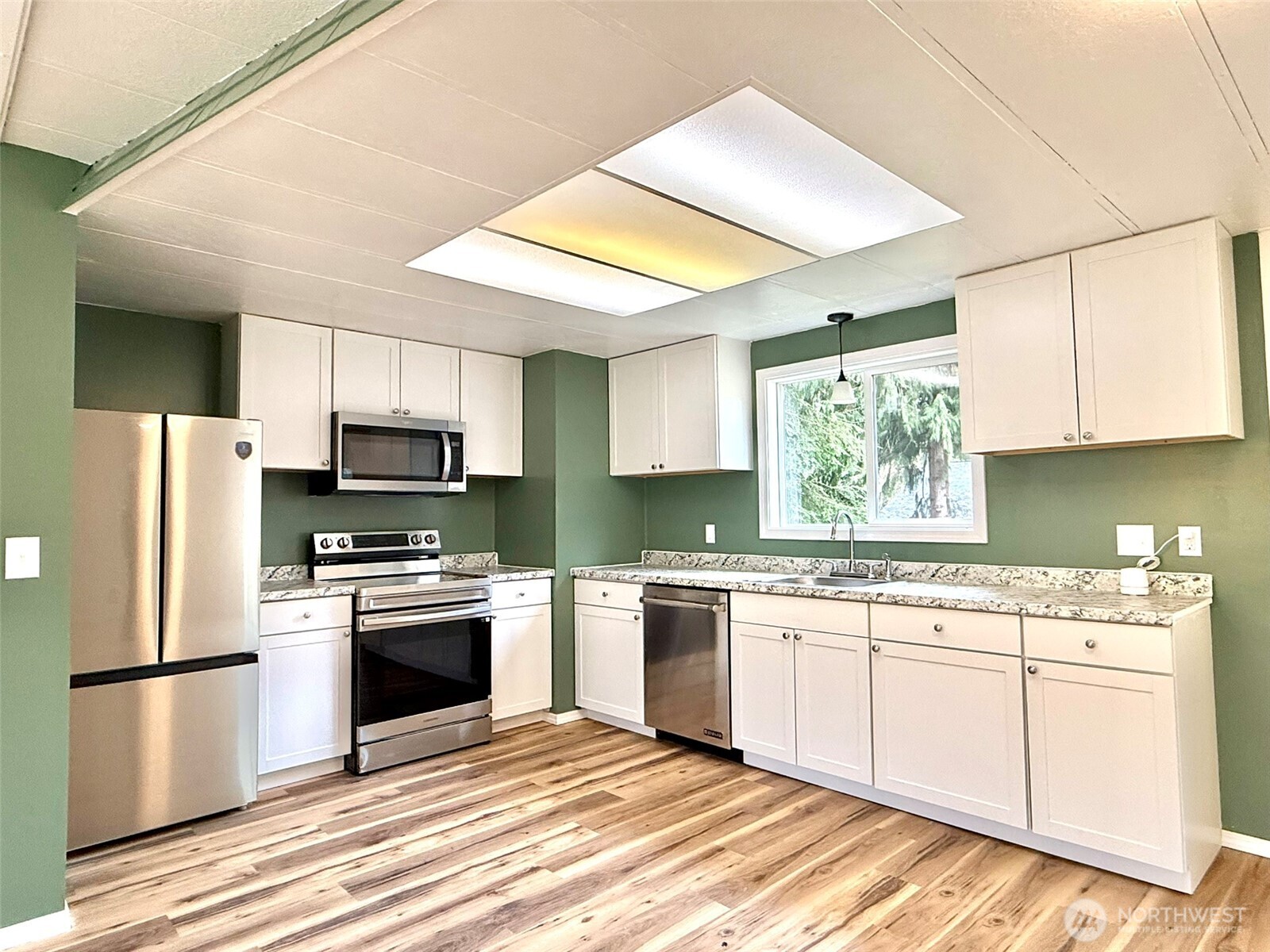 22513 South Forest Loop Road Granite Falls, WA 98252 - Photo 14 of 39 a kitchen with stainless steel appliances a stove a sink dishwasher a refrigerator with white cabinets and wooden floor