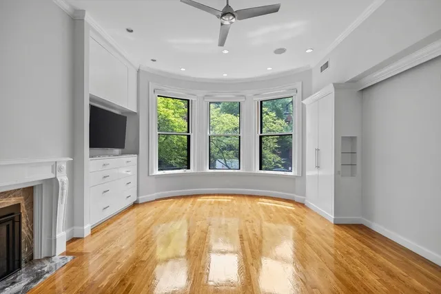 a view of an empty room with window and kitchen view