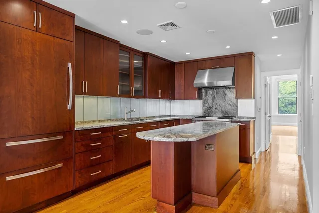 a kitchen with kitchen island granite countertop wooden cabinets and a sink