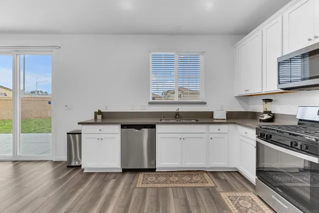 a kitchen with stainless steel appliances granite countertop a stove a sink and a microwave