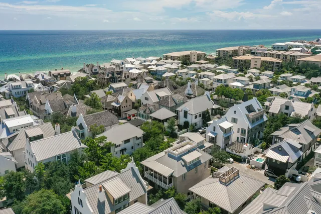 an aerial view of a city with lots of residential buildings and ocean view in back