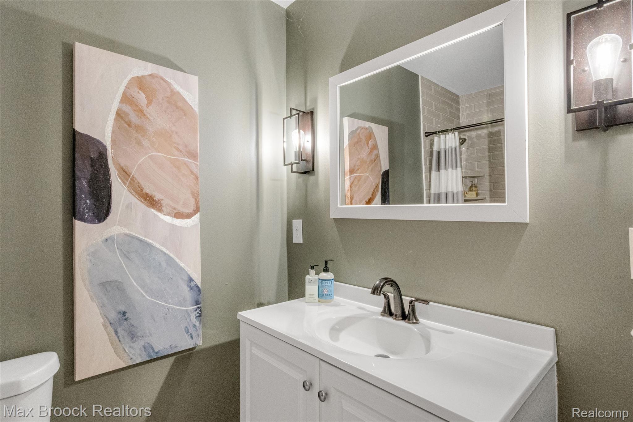 2905 Lahser Road Bloomfield Hills, MI 48304 - Photo 20 of 28 Bathroom featuring a white vanity with an integrated sink, brushed nickel faucet, and a framed mirror
