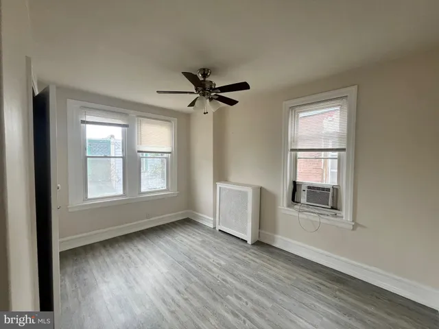 an empty room with wooden floor chandelier fan and windows