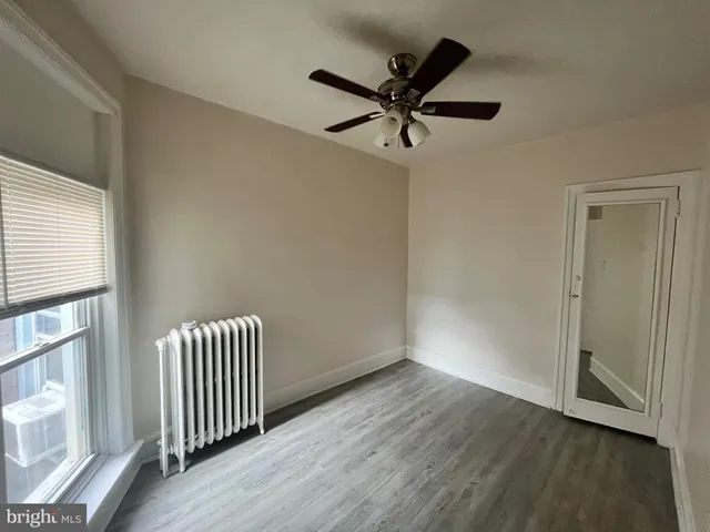 an empty room with wooden floor fan and windows