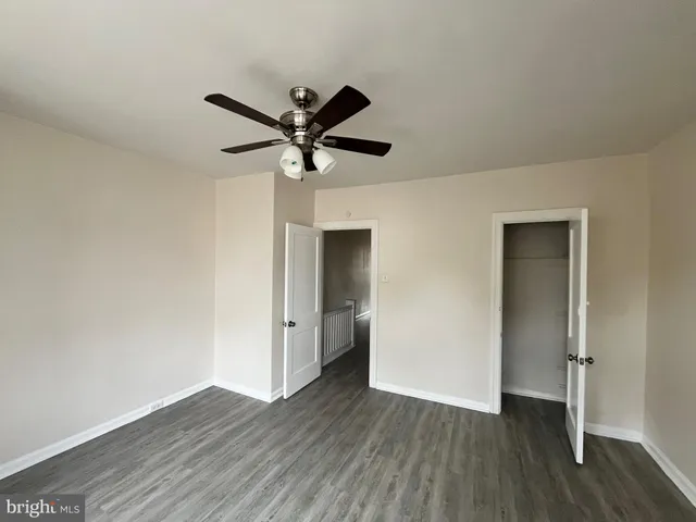 an empty room with wooden floor and a ceiling fan