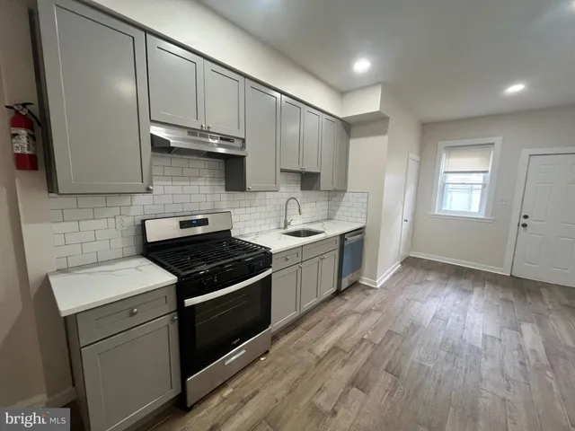 a kitchen with cabinets wooden floor and stainless steel appliances