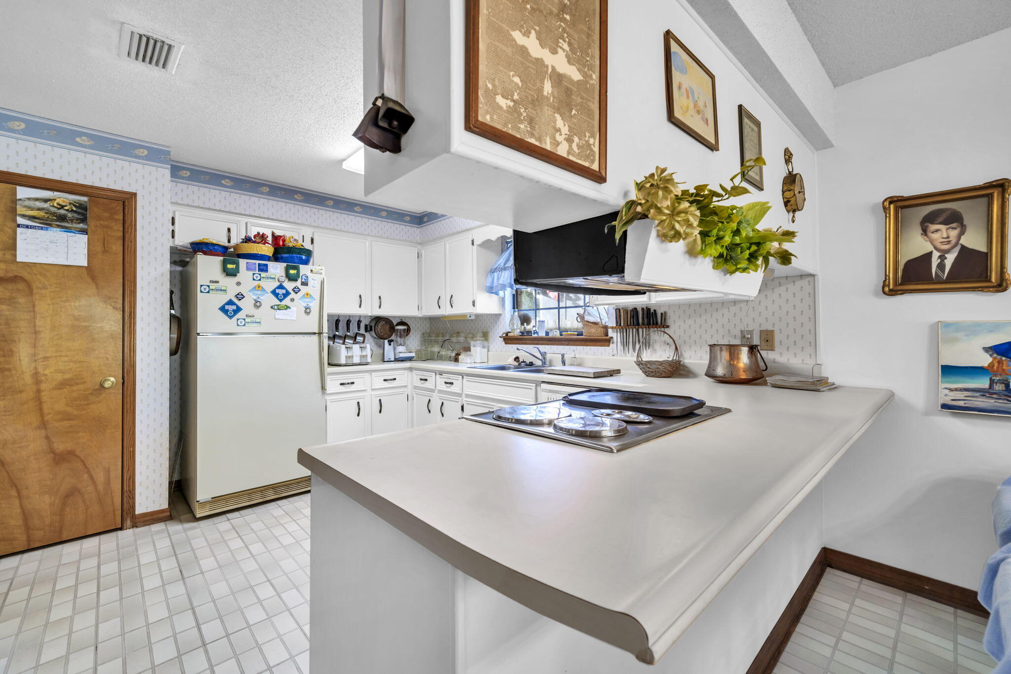392 Evergreen Circle Destin, FL 32541 - Photo 8 of 32 a white kitchen with a stove a sink a refrigerator cabinets and a dining table