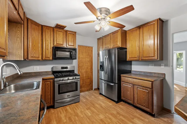 a kitchen with stainless steel appliances granite countertop a stove a sink dishwasher a refrigerator and a microwave oven with wooden floor